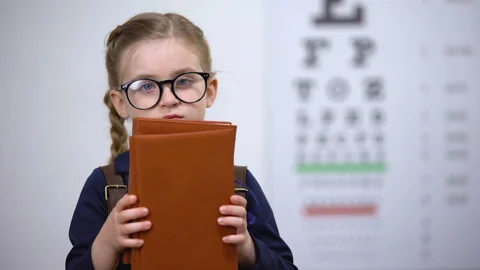 Bookworm kid in glasses hugging books, poor vision after reading too much Stock Footage