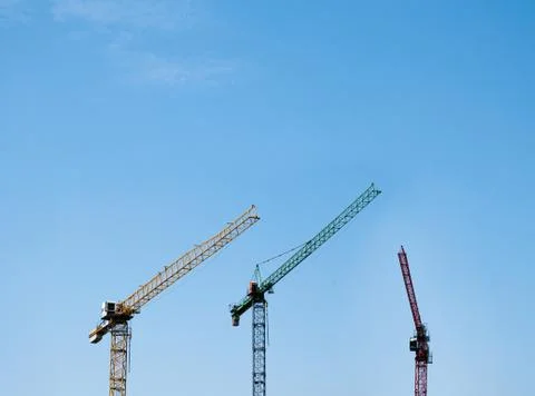 Boom cranes on a background of cloudy cloudy sky. Construction cranes on blue Stock Photos