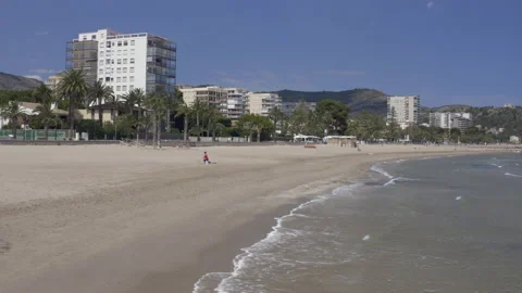 Boom down from beach apartment view to waves rolling onto sandy beach Stock-Footage 150339808