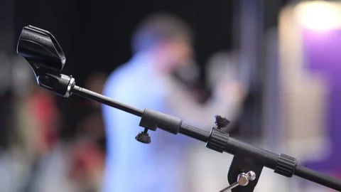 Boom mic on stand, people and lights out of focus behind Stock Footage 344687641