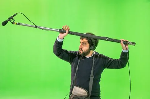 Boom microphone operator testing sound at TV studio on green key chroma Stock Photos