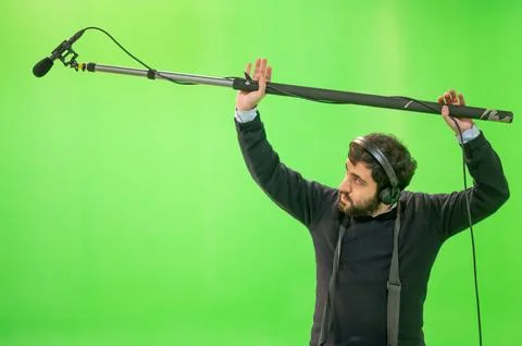 Boom microphone operator testing sound at TV studio on green key chroma Stock Photos