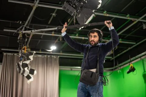 Boom microphone operator testing sound at TV studio. Stock Photos