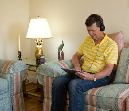 Boomer reading on tablet computer Stock Photos