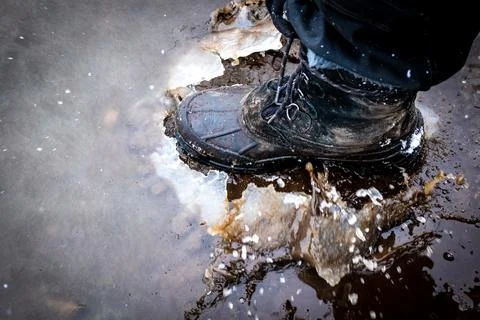 Boot cracking through an ice puddle Stock Photos