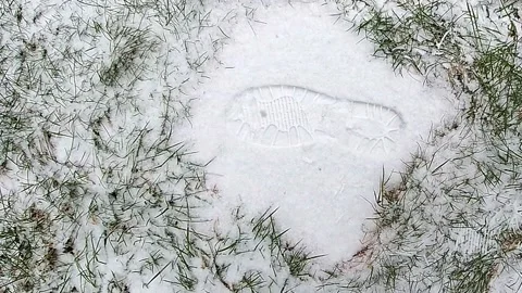 Boot print on snowy paving stone as snowflakes gently fall around. Stock Footage 148394138