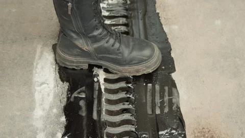 Boot striking sealed expansion joint leaving deep tread imprint, contractor Stock Footage 345527960