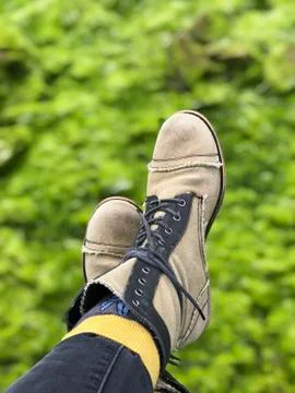 Booted feet with socks dangling over green Stock Photos