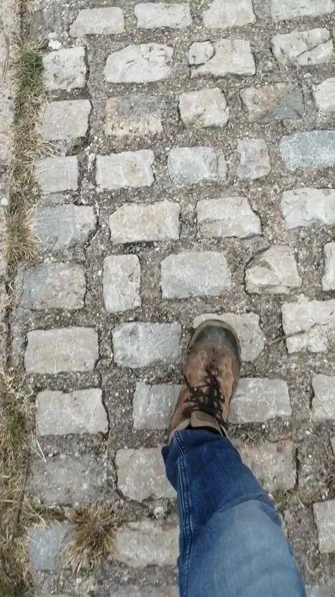 Boots and blue jeans walking on old stones (vertical video) Stock Footage 222561422