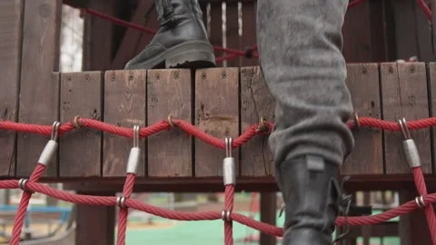 Boots confidently cross sturdy rope bridge with textured soles. Individuals in Stock Footage 337371496