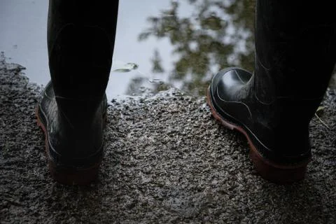 Boots on edge of puddle Stock Photos