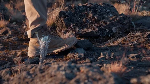Boots stepping on rocky ground during a hike in rugged terrain at sunset Vídeo Stock 296575254