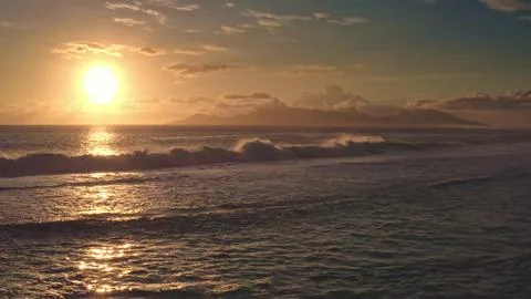 Bora Bora sunset illuminating ocean waves and distant mountains Stock Photos