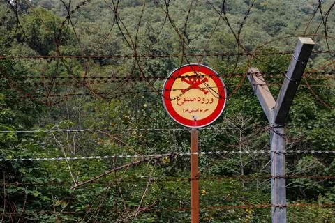Border area between Iran and Azerbaijan marked by warning signs and barbed wi Stock Photos