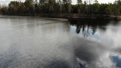 Border between ice and water at frozen lake with thin ice sky mirror the spring Stock Footage 129326541