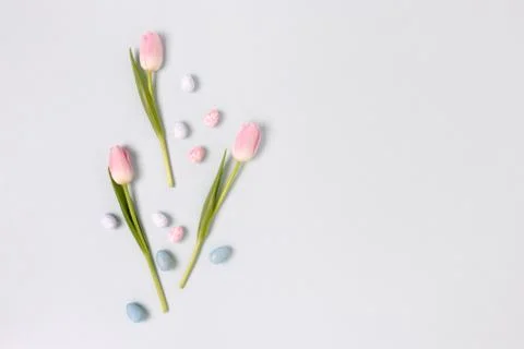 Border frame made of easter eggs and flowers on a blue pastel background. Stock Photos