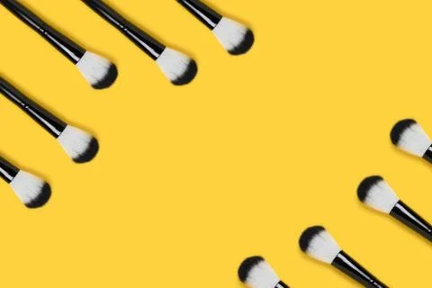 Border frame made of makeup brushes on a yellow background. Foto stock
