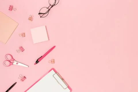 Border frame made of scattered office supplies on a pink background. Stock Photos