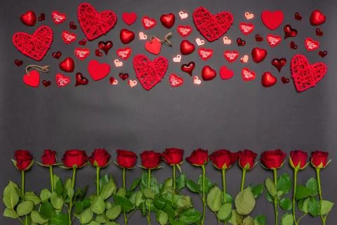 Border made of fresh red rose flowers, hearts and sweets on black background. Stock Photos