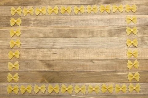 Border made of raw bow shape pasta on wood Stock Photos