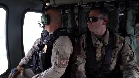 Border patrol agent and U.S. Army soldier conduct surveillance from helicopter Stock Footage 97924193