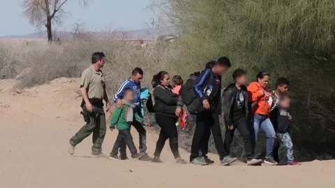 Border patrol agent escorting migrants through desert at Mexican border Stock Footage 106117462