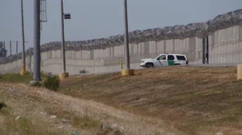 A Border Patrol car sits between fences no man's land north of Tijuana, Mexico Stock Footage 48607610