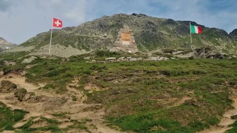 Border point at Spluga Pass showing the Italian and Swiss flags gently waving Stock Footage 340821139