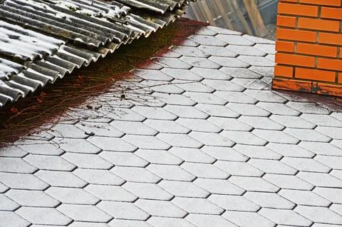 The border of two roofs with different coatings covered with fresh snow. Sele Stock Photos