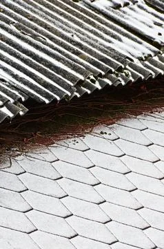 The border of two roofs with different coatings covered with fresh snow. Sele Foto stock