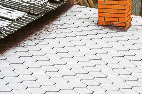 The border of two roofs with different coatings covered with fresh snow. Sele Stock Photos