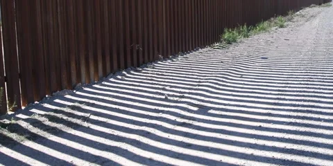 The Border Wall shadow falling on patrol road, Arizona, 4k Stock Footage 240972087