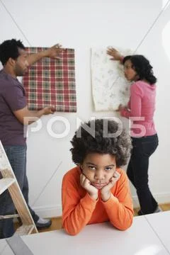 Bored African boy waiting while parents choose wallpaper Stock Photos