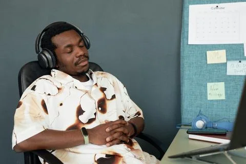 Bored Black Man Sleeping at Workplace in Headphones Tired Stock Photos