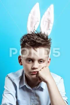 Bored boy in a light shirt and Bunny ears on a blue background Stock Photos