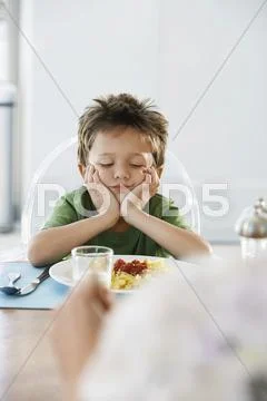 Bored Boy Sitting At Breakfast Table Stock Photos