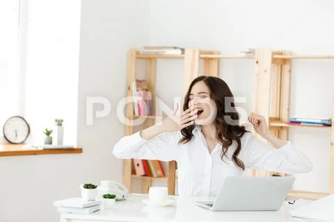 Bored business people: woman sitting at desk with closed eyes and yawning. Young Stock Photos