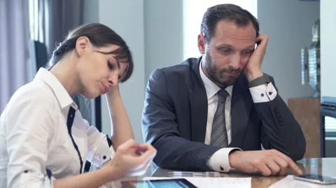 Bored businesspeople sitting by table in office Stock Footage