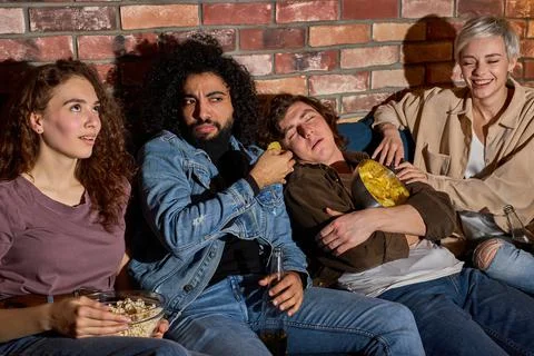 Bored Caucasian Guy Sleeping While Diverse Friends Watching Movie Online On TV Stock Photos
