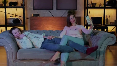 Bored couple sitting on a sofa and watching tv. Apathy and depression Stock Footage 129600227