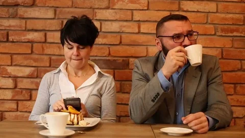 Bored couple sitting by the table at cafe, woman writing sms Stock Footage 71746748