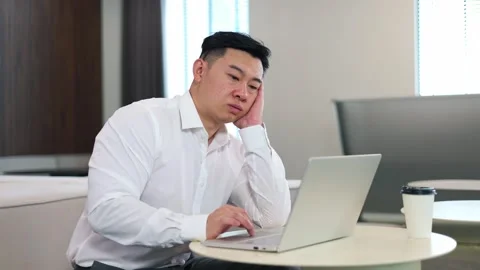 Bored employee sitting at desktop with computer and feeling apathy for work Stock Footage 251782736