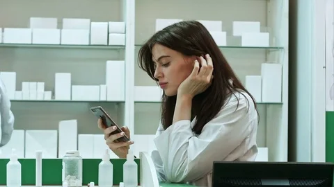 Bored female pharmacist use mobile phone at pharmacy Stock Footage 74652007