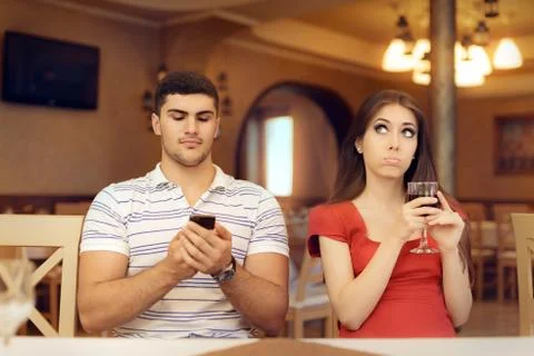 Bored Girl in a Date with Her Boyfriend Addicted to his Smartphone Stock Photos