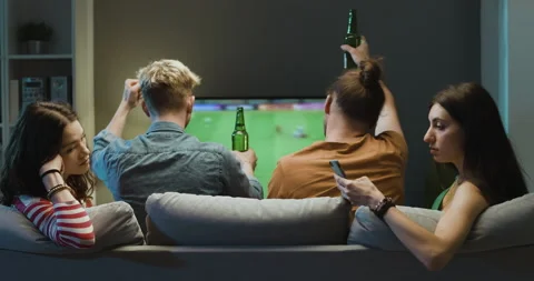 Bored girls talking together while boyfriends are watching soccer Stock Footage 297783380
