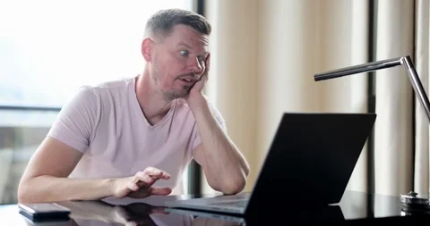 Bored man checking online laptop content sitting on table at home Video stock 262443165