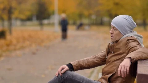 Bored man resting, sitting on a bench in autumn park, copyspace Stock Footage 120205381