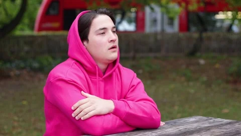 Bored man sits on bench in park and feels lonely. Unhappy guy suffering negative Vidéo 259490342