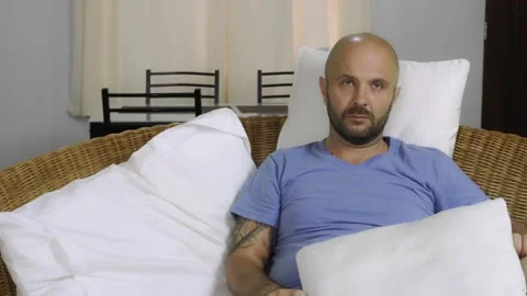 A bored man sits on the couch and switches channels on the TV. Vídeo Stock 145315251