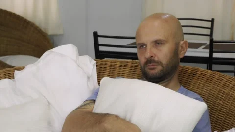 A bored man sits on the couch and switches channels on the TV. Vídeo Stock 145315301